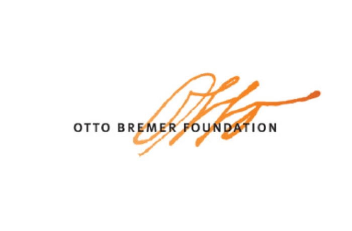 Logo of the Otto Bremer Foundation, featuring the organization’s name in black capital letters with an orange signature-like design above and behind the text, all on a white background.